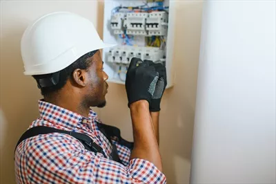 عکس برقکار مرد در حال کار بر روی تابلو برق و اتصالات الکتریکی