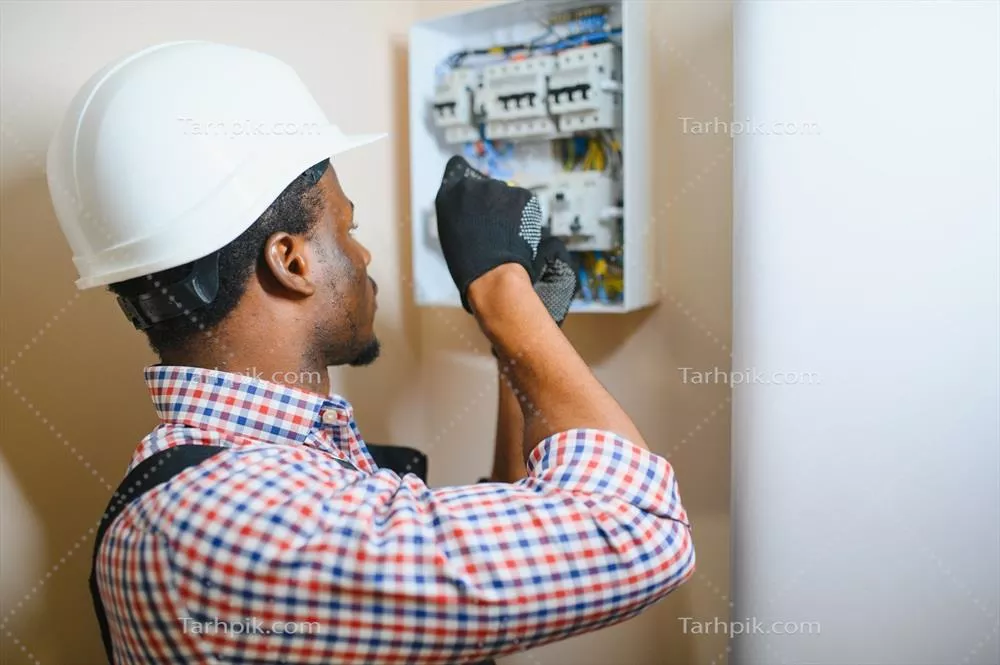عکس برقکار مرد در حال کار بر روی تابلو برق و اتصالات الکتریکی
