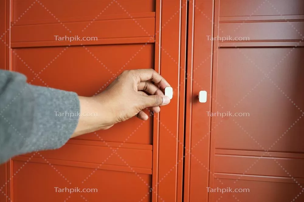 عکس مردی که در حال باز کردن درب کمد اتاق خواب است و به دنبال چیزی می گردد