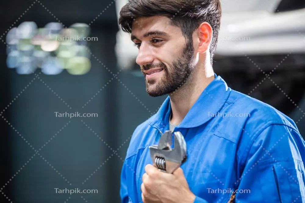 عکس مکانیک خوشحال و حرفه ای در حال بررسی خودرو در تعمیرگاه
