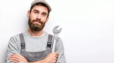 عکس مردی با ریش و کلاهی که آچار در دست دارد و در حال کار است