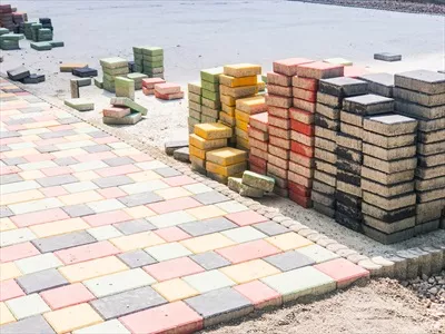 عکس توده ای از آجرهای رنگی مربع شکل در حال آماده سازی برای پیاده رو