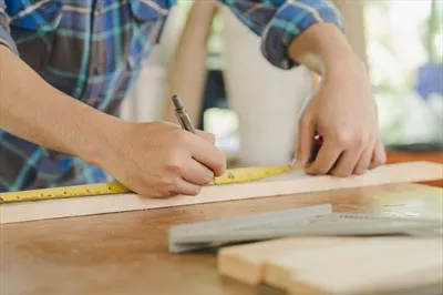 عکس کار با چوب: جوان آسیایی در حال اندازه گیری چوب برای ساخت مبلمان