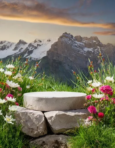 عکس پودیوم سنگی زیبا در میان گل ها و چمن سبز با نمای کوهستانی