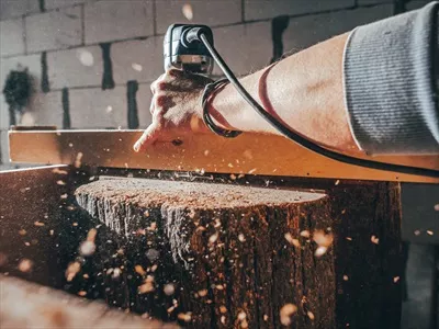 عکس نزدیک نمایی از یک نجار در حال کار با دستگاه فرز برقی