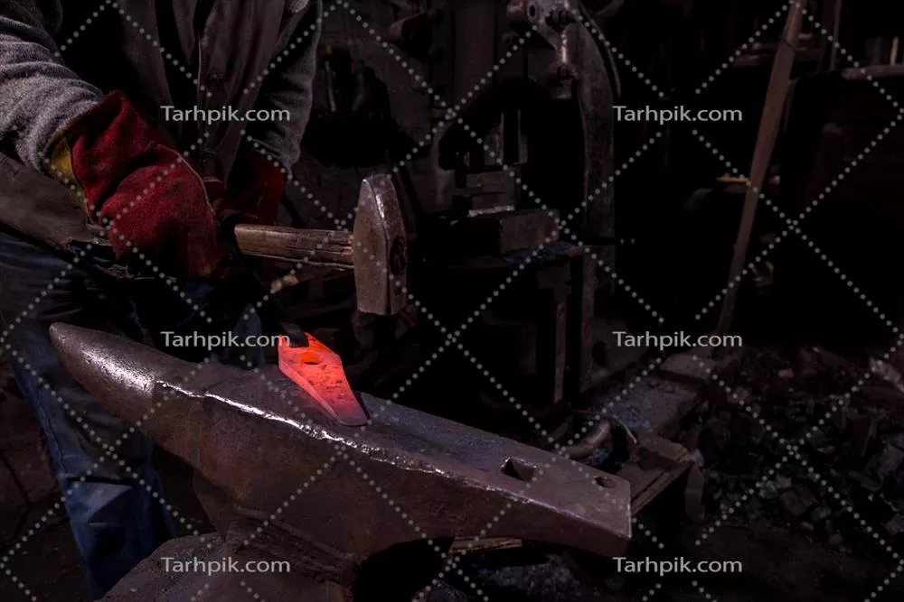 عکس هنر آهنگری: فرآیند دستی شکل دهی به فلز مذاب توسط آهنگر