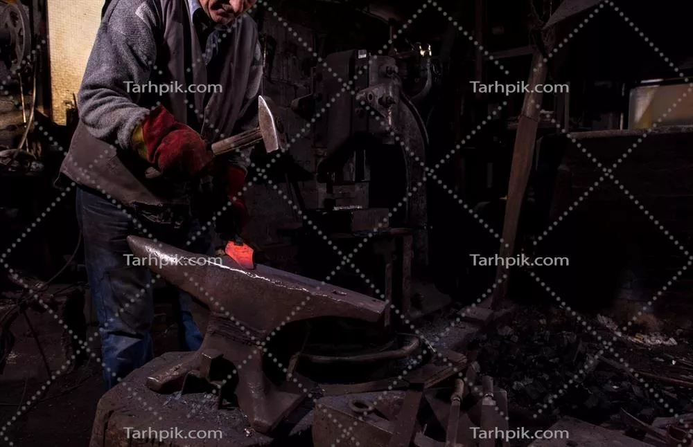 عکس هنر آهنگری: فرآیند دستی شکل دهی به فلز مذاب توسط آهنگر