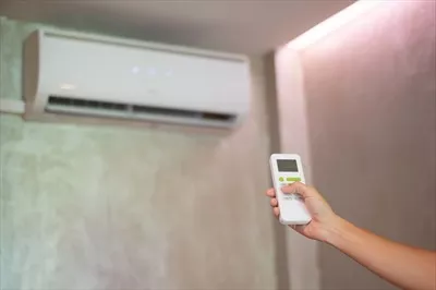 عکس استفاده از کنترل از راه دور برای تنظیم دما در محیط کار یا خانه