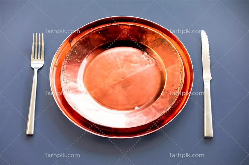 عکس نمایی زیبا از یک بشقاب خالی با کارد و چنگال فلزی در کنار آن