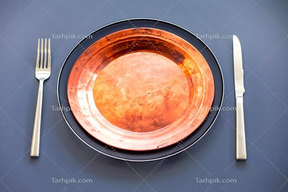 عکس نمایی زیبا از یک بشقاب خالی با کارد و چنگال فلزی در کنار آن