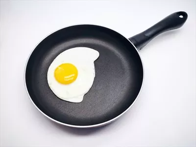 عکس تزیین تخم مرغ سرخ شده در تابه مشکی بر روی پس زمینه سفید