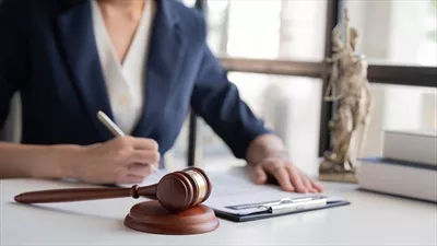عکس وکیل زن آسیایی در حال کار با ترازوی عدالت و مطالعه کتاب حقوقی