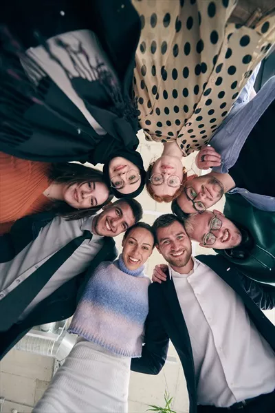 عکس گروهی متنوع از حرفه ای های کسب و کار که با همدیگر در آغوش هستند و نماد اتحاد و همبستگی را به نمایش می گذارند