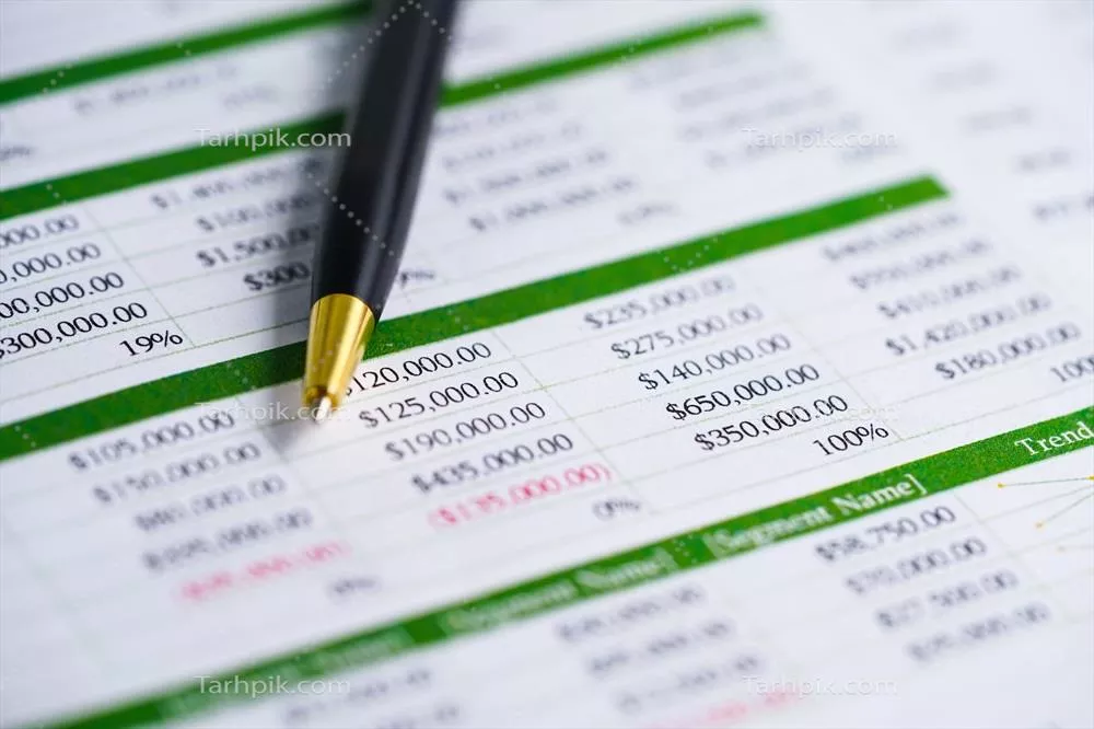 عکس جدول مالی و آماری با قلم بر روی کاغذ برای تحلیل و توسعه اقتصادی
