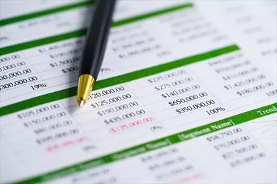 عکس جدول مالی و آماری با قلم بر روی کاغذ برای تحلیل و توسعه اقتصادی