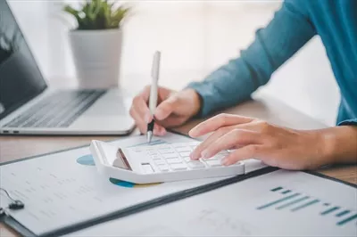 عکس تصویری نزدیک از یک فرد تجاری در حال کار با ماشین حساب و نمودار در دفتر مالی