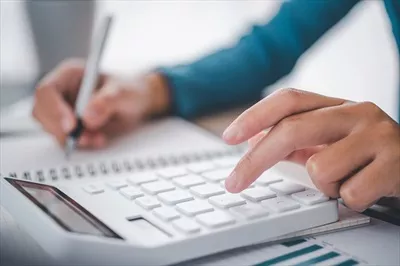 عکس تصویری نزدیک از یک فرد تجاری در حال کار با ماشین حساب و نمودار در دفتر مالی