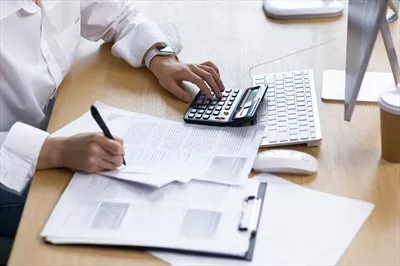 عکس نزدیک نمایی از دست یک زن کارآفرین بر روی مدارک مالی و حسابداری