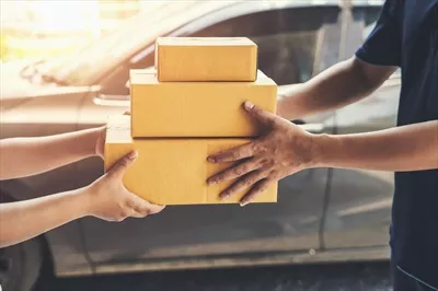 عکس تحویل دهنده بسته در حال ارائه خدمات به مشتری با جعبه ای در دست