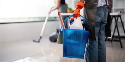 عکس نظافتچی دفتر با سطل و لوازم تمیزکاری در حال نظافت محیط کار