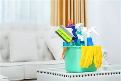 عکس مجموعه ای از لوازم نظافت بر روی میز در اتاق با سطل و محصولات تمیزکننده