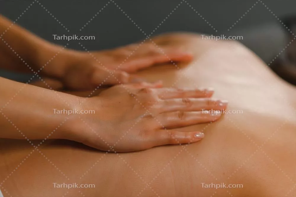 عکس ماساژور در حال انجام ماساژ بر روی کمر زن در سالن اسپا
