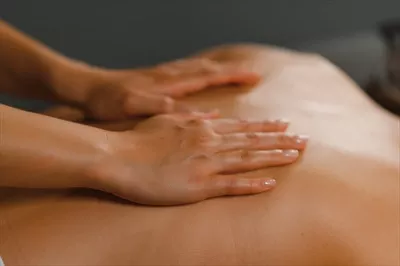 عکس ماساژور در حال انجام ماساژ بر روی کمر زن در سالن اسپا
