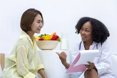 عکس مشاوره تغذیه سالم توسط متخصص تغذیه آفریقایی-آمریکایی با کاسه ای از میوه ها و سبزیجات