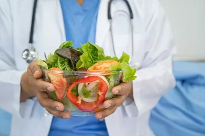 عکس متخصص تغذیه در حال ارائه سبزیجات تازه و سالم به بیمار