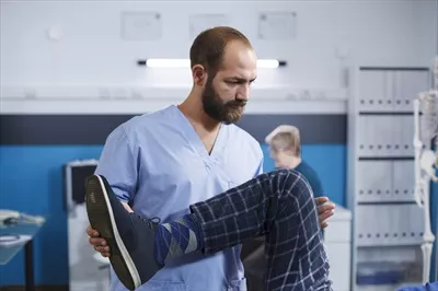 عکس پرستار ارتوپدی در حال کمک به بیمار با آسیب زانو در فیزیوتراپی