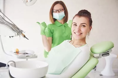 عکس زنی جوان که از کار دندانپزشک راضی است و انگشت شستش را بالا برده است