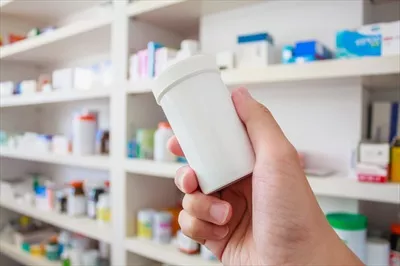 عکس نگاهی به داروخانه: دست گرفتن بطری دارو در محیط داروخانه