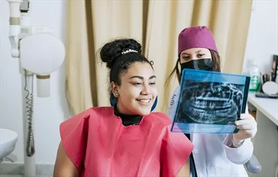 دندانپزشک در حال بررسی عکس رادیوگرافی با بیمار و توضیحات لازم