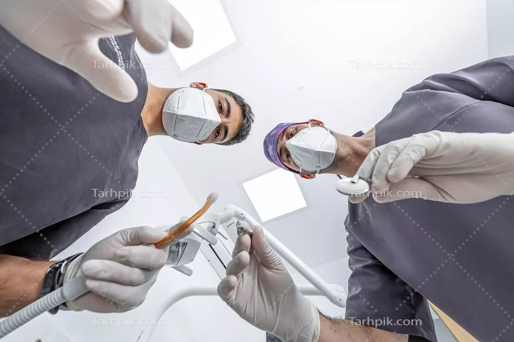 عکس دندانپزشک و دستیار آماده برای درمان بیمار در مطب دندانپزشکی