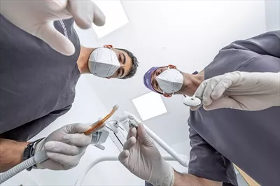 عکس دندانپزشک و دستیار آماده برای درمان بیمار در مطب دندانپزشکی