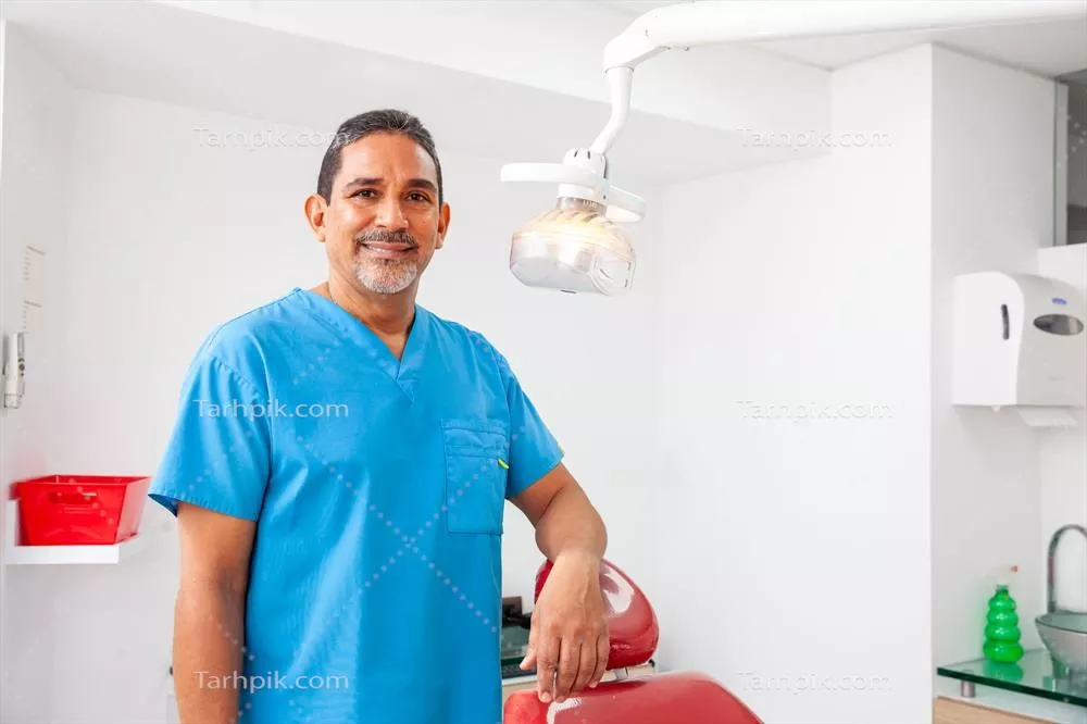 عکس پرتره ای از یک دندانپزشک مرد میانسال در دفتر کارش