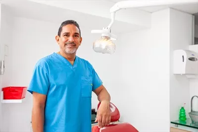 عکس پرتره ای از یک دندانپزشک مرد میانسال در دفتر کارش