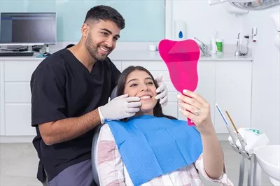عکس دندانپزشک و بیمار در حال بررسی و تحسین دندان ها با دقت و توجه
