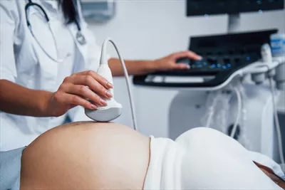 عکس پزشک زن در حال انجام سونوگرافی برای یک زن باردار در بیمارستان