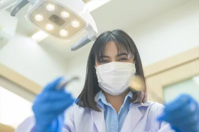 عکس دندانپزشک زن در حال بررسی دندان های بیمار با ابزارهای دندانپزشکی