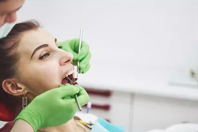 عکس دندانپزشک در حال درمان یک بیمار زن: پیشگیری زودهنگام و بهداشت دهان
