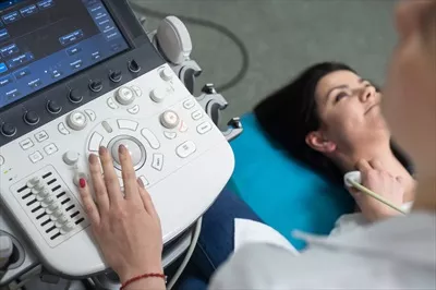 عکس پزشک زن متخصص غدد در حال انجام سونوگرافی بر روی بیمار زن در مطب