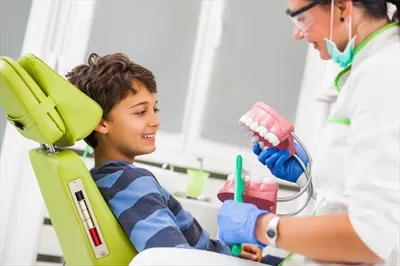 عکس کودکی که در مطب دندانپزشکی منتظر نوبت است و احساس نگرانی می کند