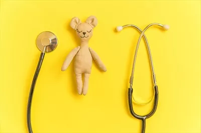 عکس طراحی مینیمالیستی اسباب بازی خرس و تجهیزات پزشکی در پس زمینه زرد