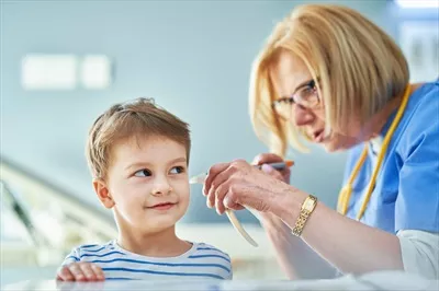 عکس پزشک اطفال در حال معاینه کودکان کوچک در کلینیک برای بررسی گوش ها