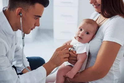 عکس پزشک جوان اطفال در کلینیک با کمک مادر، در کنار نوزاد در روز