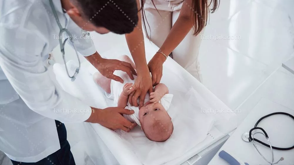 عکس پزشک جوان اطفال در حال معاینه نوزاد در کلینیک در طول روز