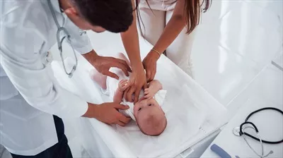 عکس پزشک جوان اطفال در حال معاینه نوزاد در کلینیک در طول روز