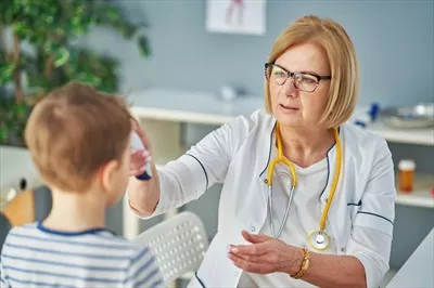 عکس پزشک اطفال در حال معاینه کودکان کوچک در کلینیک و بررسی دما