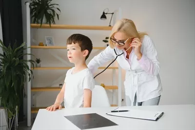 عکس پزشک اطفال در حال معاینه یک پسر بچه برای بررسی سلامت قلب و ریه